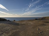 an ocean on the horizon of a desert landscape, with rocky shoreline on right side