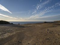 an ocean on the horizon of a desert landscape, with rocky shoreline on right side