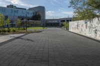 a city street surrounded by grass and tall buildings at the end of a street there is a paved pathway in front of the building