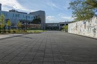 a city street surrounded by grass and tall buildings at the end of a street there is a paved pathway in front of the building