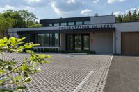 an entrance to the presentation gallery in a large city setting with trees in the background