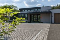 an entrance to the presentation gallery in a large city setting with trees in the background
