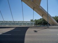 a truck driving across a bridge near a street corner near buildings and a bridge with many cables