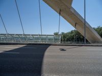 a truck driving across a bridge near a street corner near buildings and a bridge with many cables