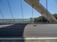 a truck driving across a bridge near a street corner near buildings and a bridge with many cables