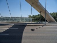 a truck driving across a bridge near a street corner near buildings and a bridge with many cables