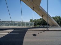 a truck driving across a bridge near a street corner near buildings and a bridge with many cables