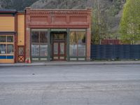 a red fire hydrant sitting in front of an old store window and building next to an open air field