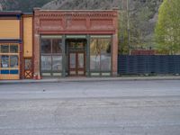 a red fire hydrant sitting in front of an old store window and building next to an open air field