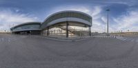 an empty parking lot with a curved building and some steps to the side, on the other side