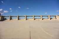 there is a dirt field with concrete walls on it and a concrete walkway above the concrete wall