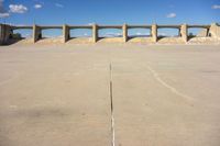 there is a dirt field with concrete walls on it and a concrete walkway above the concrete wall