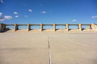 there is a dirt field with concrete walls on it and a concrete walkway above the concrete wall