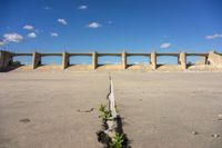 there is a dirt field with concrete walls on it and a concrete walkway above the concrete wall