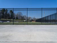 an iron gate in a parking lot near some cars with no wheels or people behind