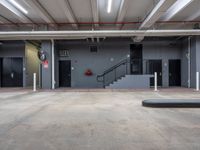 a garage filled with lots of concrete floors and stairs inside of it and closed fire escape doors