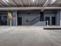 a garage filled with lots of concrete floors and stairs inside of it and closed fire escape doors