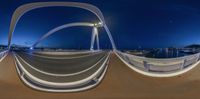 a fisheye view of a street bridge at night in the middle of nowhere on the sea