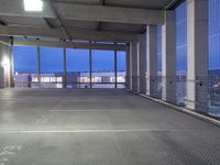 the view of a parking garage through a large glass door at night on a rooftop