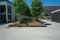 a large concrete courtyard with a brick planter on the bottom and trees in it