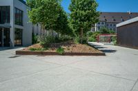 a large concrete courtyard with a brick planter on the bottom and trees in it