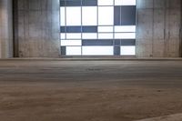 an empty warehouse with some windows behind it and floor tiles on the ground and one door opened