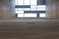 an empty warehouse with some windows behind it and floor tiles on the ground and one door opened