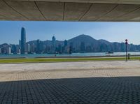 an empty park is on the edge of a large bay near buildings and water with green lawning