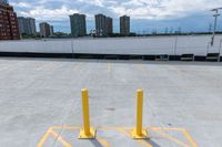 parking lot with yellow barriers in the background and tall buildings across it in a city