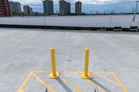 parking lot with yellow barriers in the background and tall buildings across it in a city