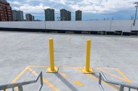 parking lot with yellow barriers in the background and tall buildings across it in a city