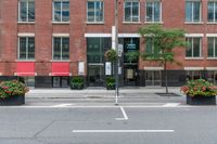 a red building and black plant pots with flowers and red ribbon on it in the street