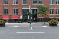 a red building and black plant pots with flowers and red ribbon on it in the street