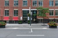 a red building and black plant pots with flowers and red ribbon on it in the street