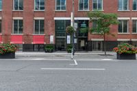 a red building and black plant pots with flowers and red ribbon on it in the street