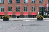 a red building and black plant pots with flowers and red ribbon on it in the street