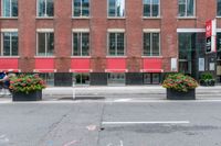 a red building and black plant pots with flowers and red ribbon on it in the street