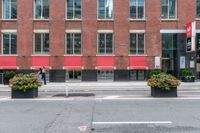 a red building and black plant pots with flowers and red ribbon on it in the street