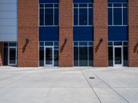 large windows in front of a brick building on the side of the road, with metal doors and a fire hydrant