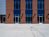 large windows in front of a brick building on the side of the road, with metal doors and a fire hydrant