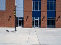 large windows in front of a brick building on the side of the road, with metal doors and a fire hydrant