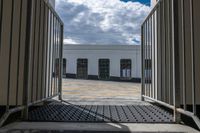 a gate with the doorway open showing a building and a cloudy sky in the background