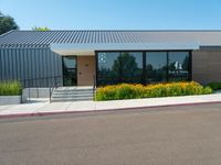 a metal and glass building with large windows in front of it and a parking space near the curb