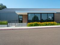 a metal and glass building with large windows in front of it and a parking space near the curb