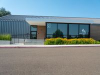 a metal and glass building with large windows in front of it and a parking space near the curb