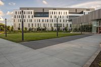 a city street surrounded by grass and tall buildings at the end of a street there is a paved pathway in front of the building