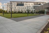 a city street surrounded by grass and tall buildings at the end of a street there is a paved pathway in front of the building