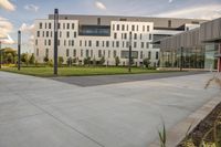 a city street surrounded by grass and tall buildings at the end of a street there is a paved pathway in front of the building