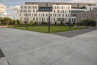 a city street surrounded by grass and tall buildings at the end of a street there is a paved pathway in front of the building