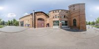 the 360 - camera photo shows the entrance and building to a public center with a man in the distance